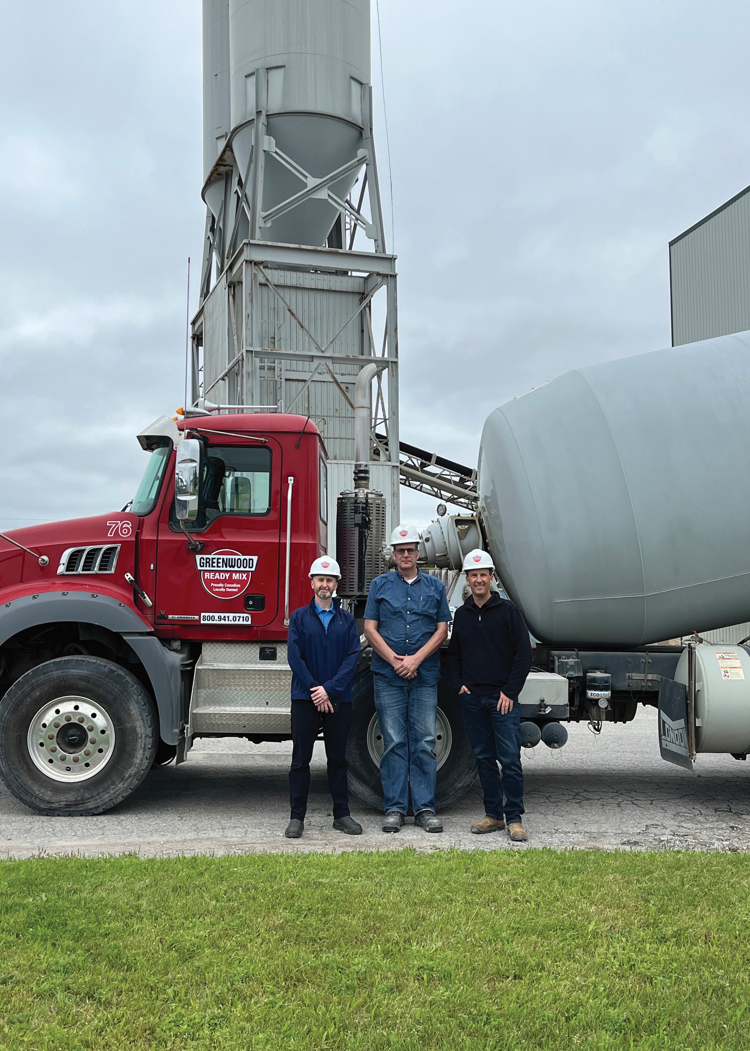 Men standing in front of a cement truck 